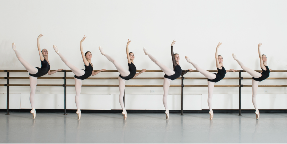six ballet students at the barre in attitude position